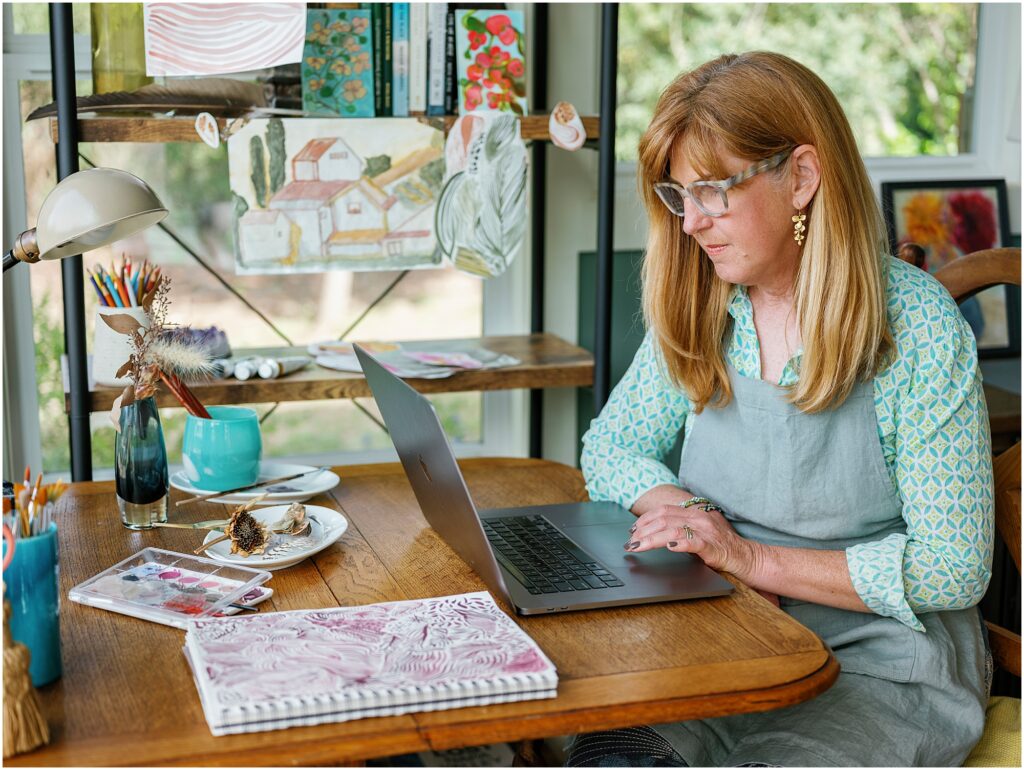 woman working at a desk with an apron and laptop photographed by Krista Marie Photography, a Bay Area personal brand photographer